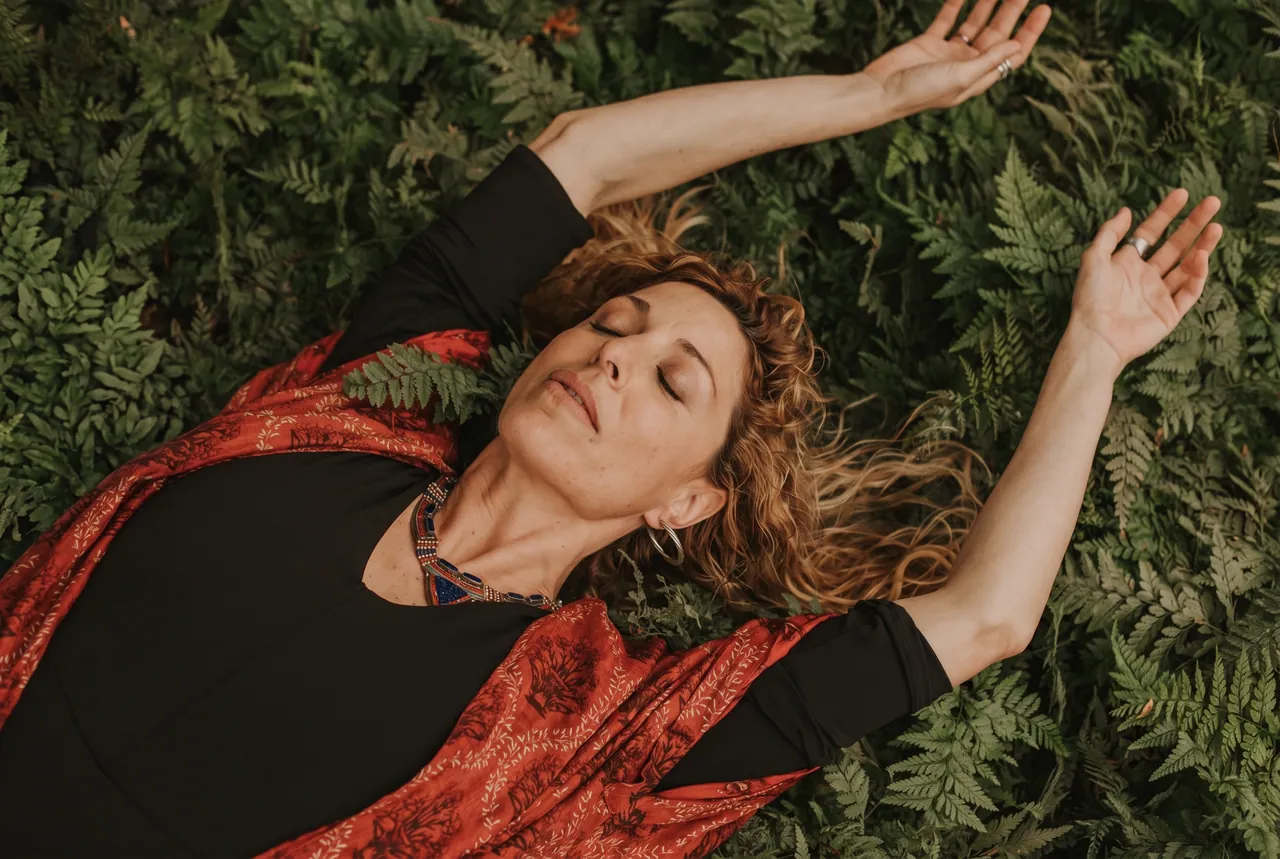 Carmen tumbada entre helechos, con un kimono rojo y los ojos cerrados