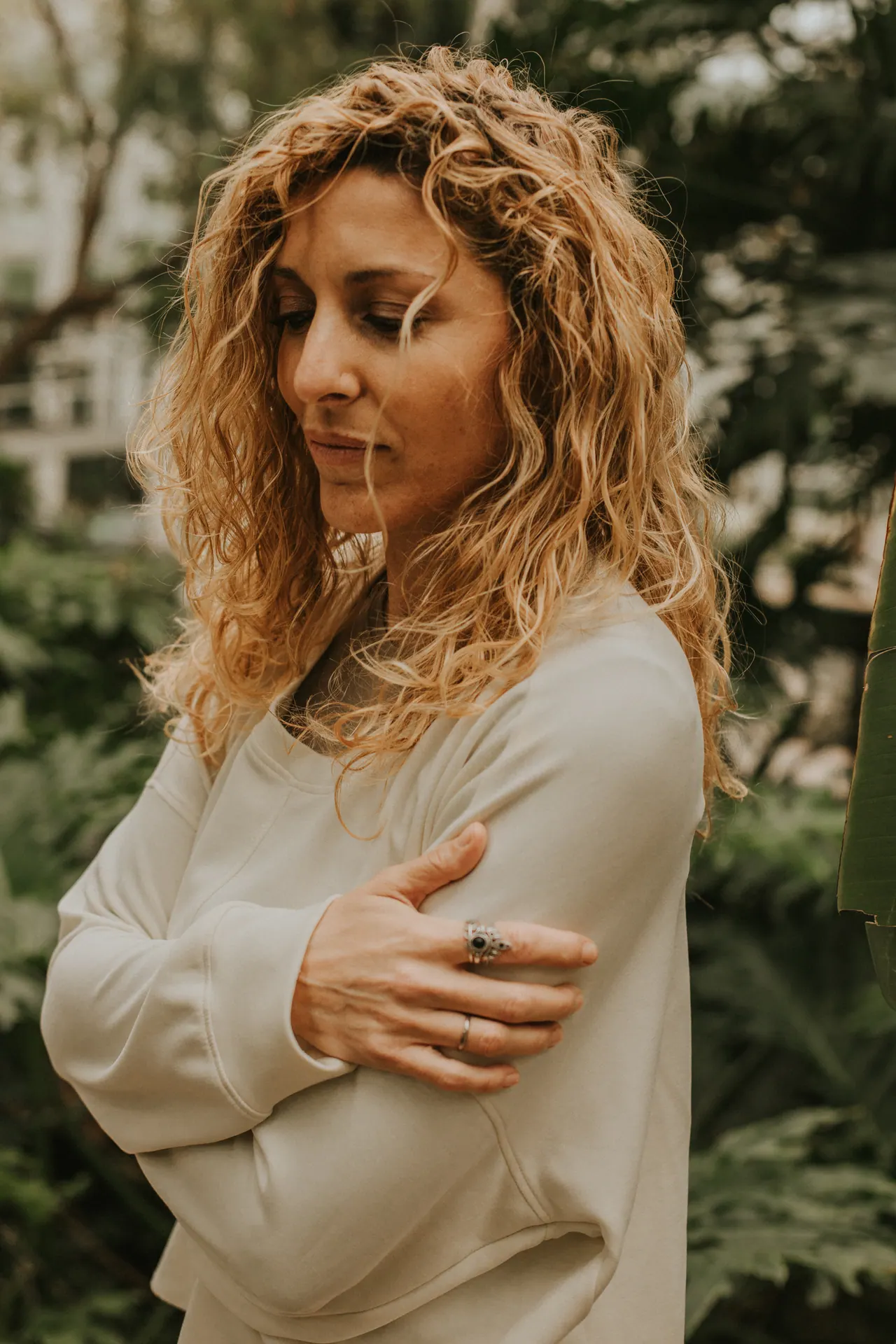 Carmen mira hacia abajo, con un jersey claro, entre las plantas