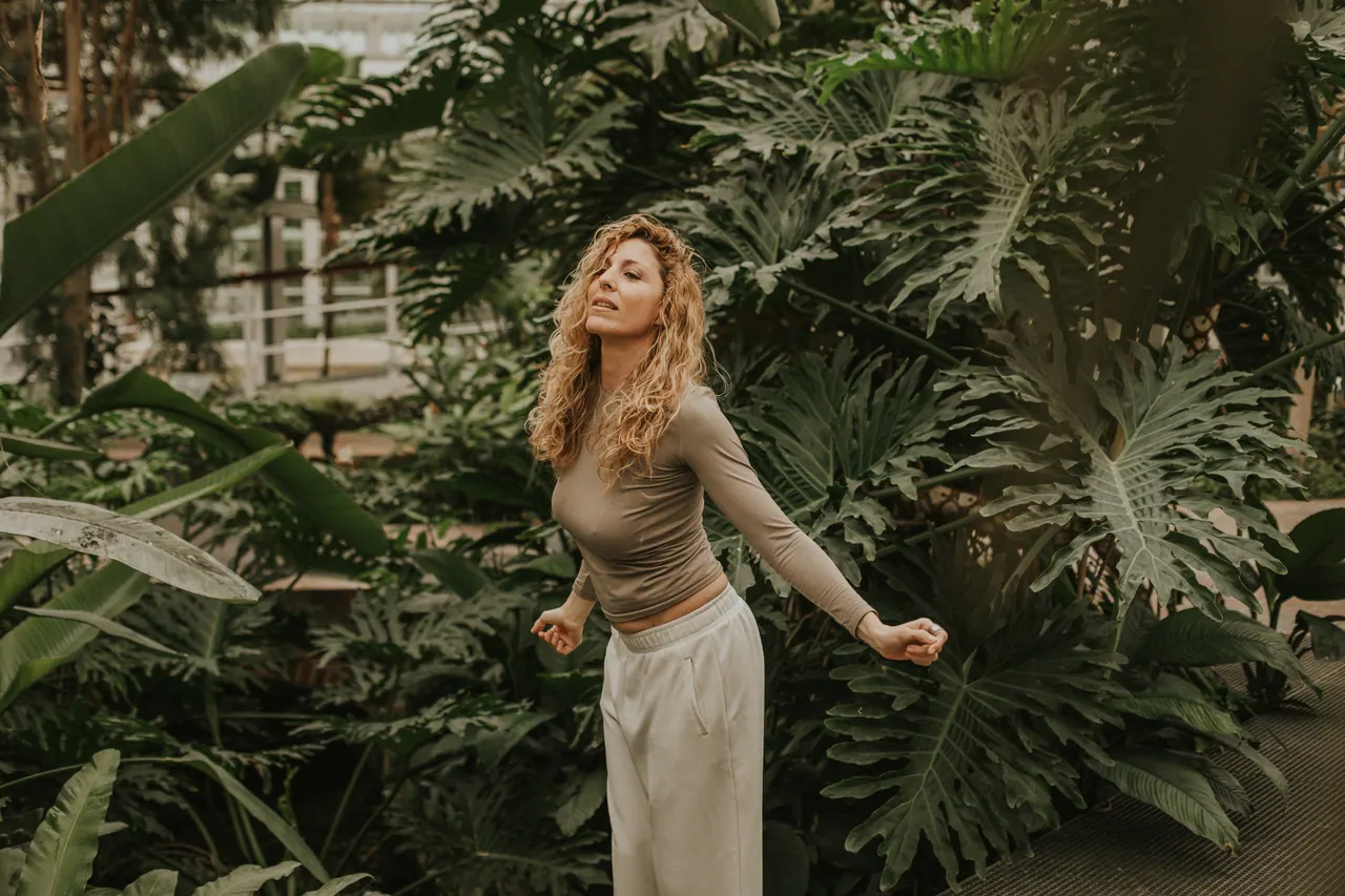 Carmen continúa el baile con los brazos en movimiento entre las hojas